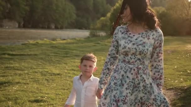 Femme marche avec son fils à travers le parc, voyage enfants, le gamin tient la main des mamans — Video