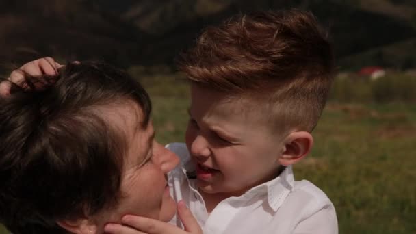 孫は祖母に近づく。彼は彼女の首の周りに腕を置く。ラブ・グラン — ストック動画