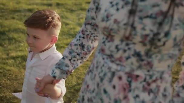 Frau läuft mit Sohn durch Park, reist mit Kindern, das Kind hält Mamas Hand — Stockvideo