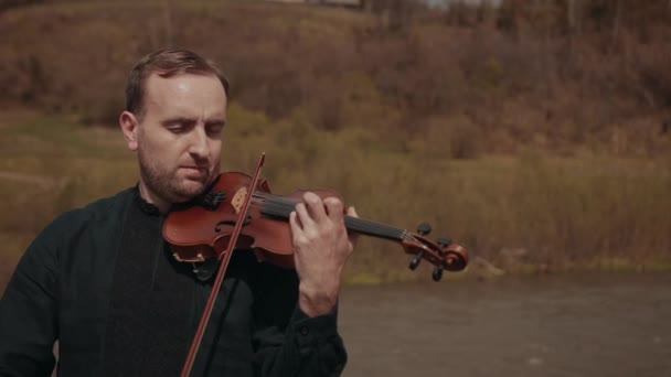 小提琴手在桥上，街头艺人在外面拉小提琴。快速河 — 图库视频影像