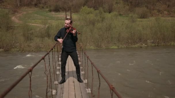 Violinista sul ponte, interprete di strada che suona il violino, fuori. Fiume Swift — Video Stock