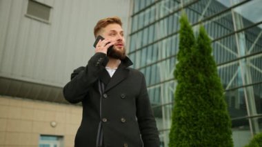 Mutlu, heyecanlı genç iş adamı cep telefonuyla konuşuyor. Çekici bir iş.