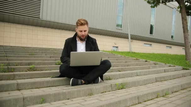 Hombre elegante guapo trabajando fuera, portátil enfocado, disfrutando, hipster barbudo — Vídeos de Stock