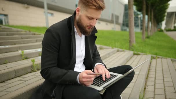 Nahaufnahme junger Mann hält Kreditkarte in der Hand und benutzt Computer-Laptop online — Stockvideo