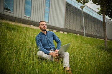 Yönetici dizüstü bilgisayar tutuyor, ofis dışında, genç işadamı bilgisayar kullanıyor.