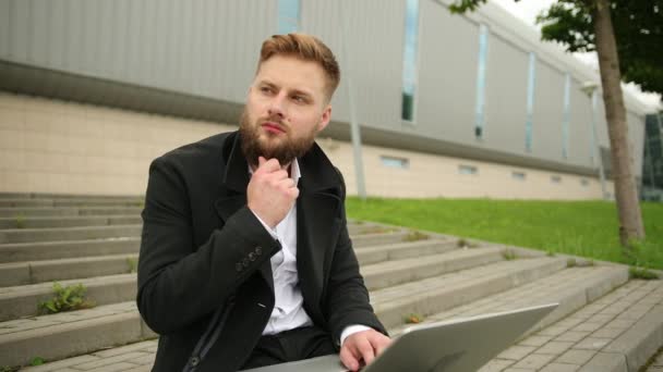 Przystojny elegancki mężczyzna pracujący na zewnątrz, skupiony laptop, cieszący się brodatym hipsterem — Wideo stockowe