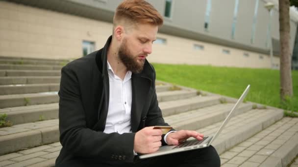 Nahaufnahme junger Mann hält Kreditkarte in der Hand und benutzt Computer-Laptop online — Stockvideo