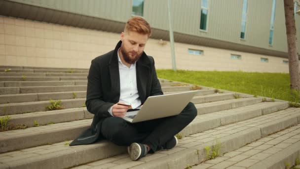 Conceito de compras online. Jovem barbudo empresário segurando um cartão de crédito — Vídeo de Stock