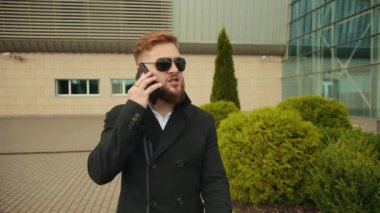 Endişeli iş lideri dışarıda akıllı telefon diye bağırıyor. Genç adam konuşuyor.