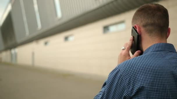 Zadní pohled na obchodníka mluvícího po telefonu, obchodníka s mobilem, venku — Stock video