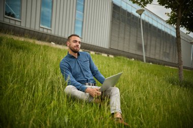 Yönetici dizüstü bilgisayar tutuyor, ofis dışında, genç işadamı bilgisayar kullanıyor.