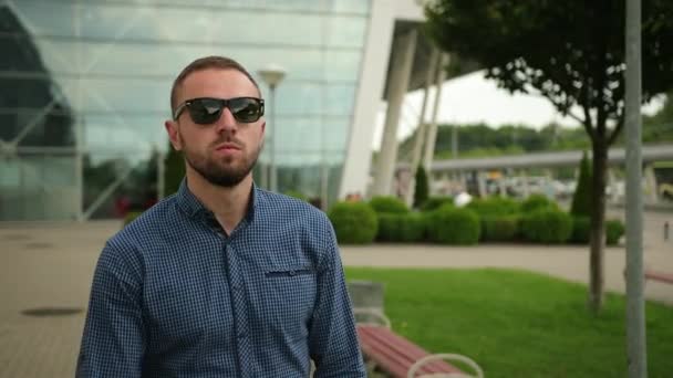 Retrato de gay guay con camisa azul. Mirando hacia adelante, hombre poniéndose gafas de sol — Vídeos de Stock