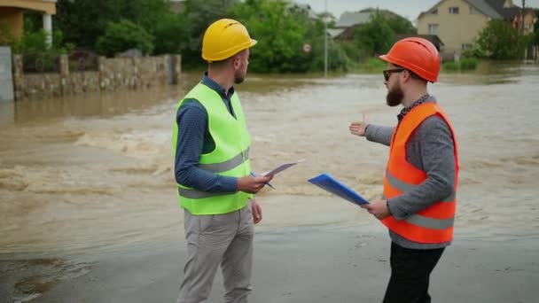To mandlige ingeniører løser oversvømmelsesproblemet. Naturkatastrofe store oversvømmelser – Stock-video