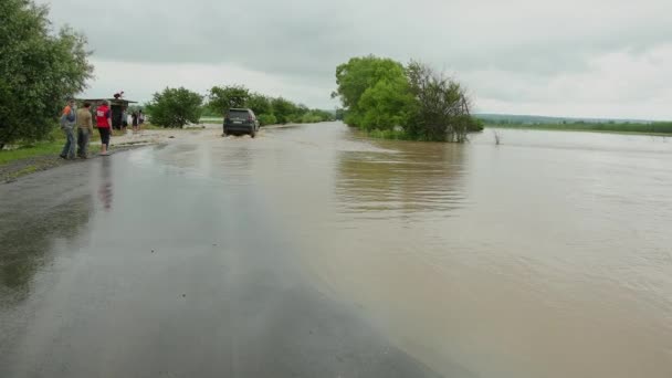 Carros que conduzem na estrada inundada durante uma inundação causada pela chuva forte, água da chuva — Vídeo de Stock