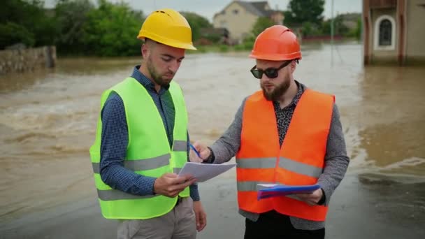 Dos ingenieros masculinos resuelven el problema de inundación. Desastre natural grandes inundaciones — Vídeo de stock