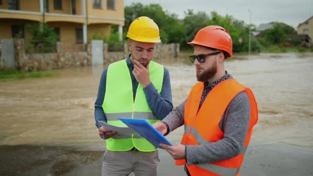 Dua insinyur laki-laki memecahkan masalah banjir. Bencana alam banjir besar — Stok Video