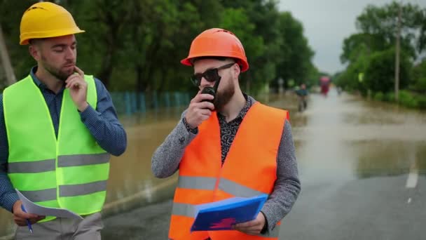 Οι άντρες μηχανικοί λύνουν προβλήματα πλημμύρας. Καταστροφή που προκλήθηκε μετά από μαζικές καταστροφές — Αρχείο Βίντεο