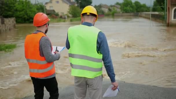 Οι άντρες μηχανικοί λύνουν προβλήματα πλημμύρας. Καταστροφή που προκλήθηκε μετά από μαζικές καταστροφές — Αρχείο Βίντεο
