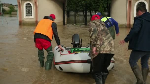 Sobrevivientes de inundación sentados en bote inflable rescatados por un par de rescatistas. Familia — Vídeo de stock
