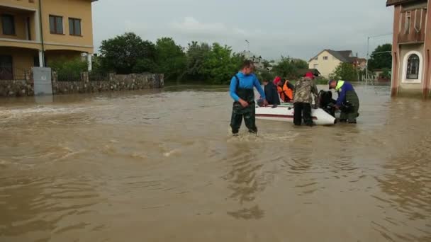 Overlevenden van overstromingen die in een opblaasbare boot zitten, gered door een paar redders. Gezin — Stockvideo