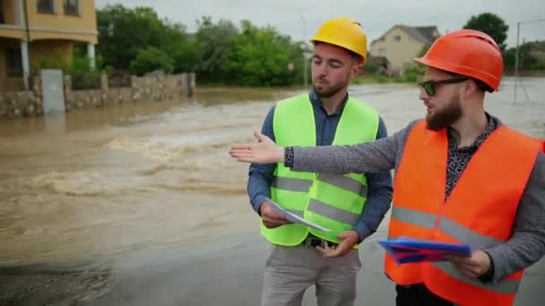 Два инженера-мужчины решают проблему наводнения. Сильное наводнение — стоковое видео