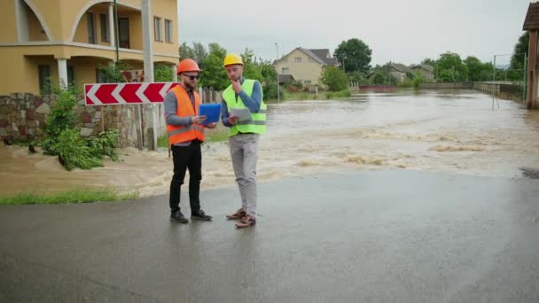 Инженеры-мужчины решают проблему наводнения. Разрушения, вызванные массовыми катастрофами — стоковое видео