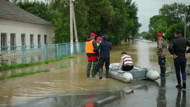 Sobrevivientes de inundación sentados en bote inflable rescatados por un par de rescatistas. salvado — Vídeo de stock