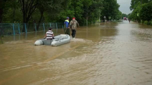 Ocaleni z powodzi, siedzący na nadmuchiwanej łodzi, uratowani przez parę ratowników. zapisane — Wideo stockowe