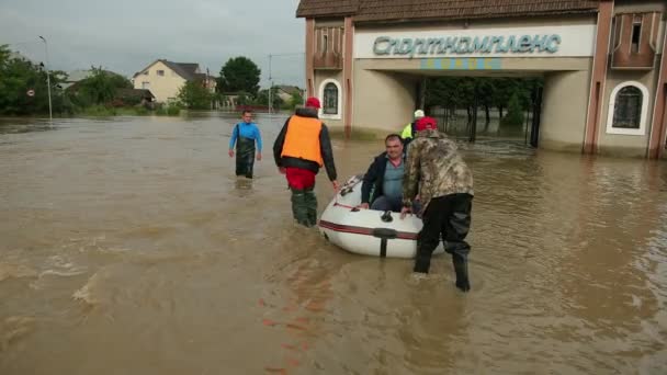 Sopravvissuti alle inondazioni seduti su una barca gonfiabile soccorsi da due soccorritori. Famiglia — Video Stock