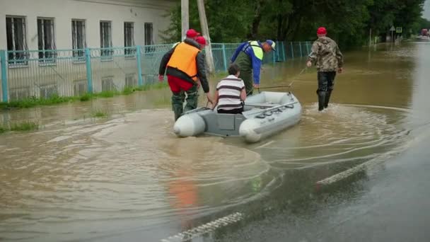 Überlebende der Überschwemmungen sitzen in einem Schlauchboot, das von zwei Rettern gerettet wird. gespart — Stockvideo