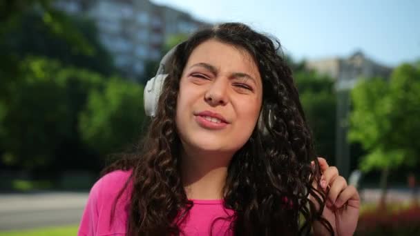 Het dragen van roze t-shirt luisteren naar muziek met headset en genieten van wandelen buiten — Stockvideo