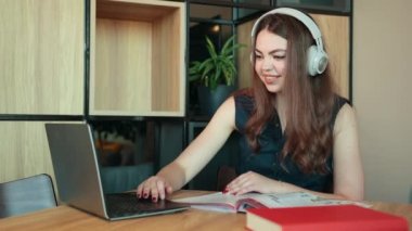 Genç bir kadın evdeki dizüstü bilgisayarında video görüşmesi yapıyor. Gülümseyen kız öğrenci