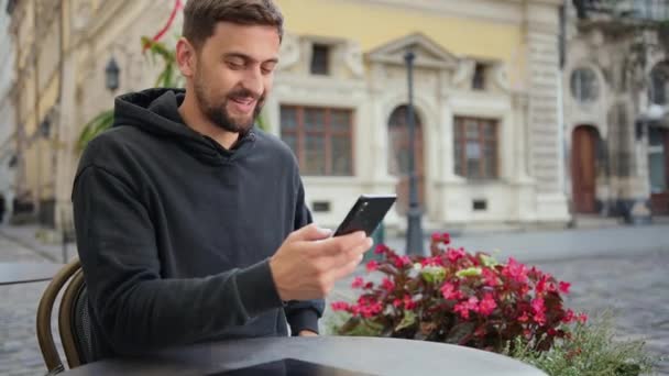 Hipster kerel met mobiele smartphone digitale camera praat terwijl zitten in cafe — Stockvideo