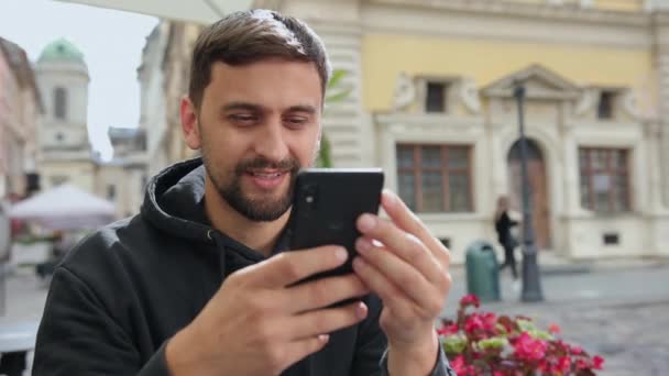 Schöner männlicher Student mit Smartphone. Lächelnder Mann macht Videoanruf mobil — Stockvideo