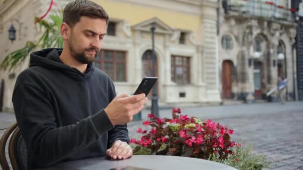 Hipster chico con teléfono inteligente móvil cámara digital habla mientras está sentado en la cafetería — Vídeo de stock