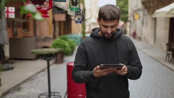 Hombre barbudo guapo con tableta en las calles, retrato de sonrisa confiada — Vídeos de Stock