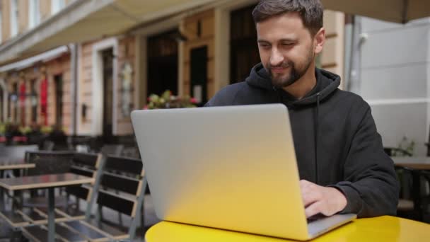 Edukacja domowa, szkolenia online, praca poza biurem. Facet siedzi przy biurku i patrzy na komputer. — Wideo stockowe