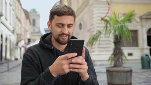 Hombre guapo estudiante usando teléfono inteligente. Sonriente hombre haciendo videollamada móvil — Vídeos de Stock