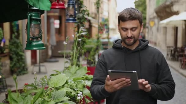 Knappe bebaarde man met tablet in de straten, portret van zelfverzekerde glimlach — Stockvideo
