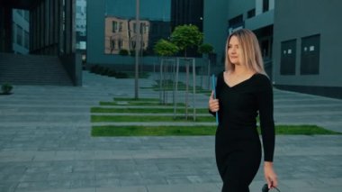 Dışarıda güneş gözlüklü bir kız var, mavi elleri klasör gibi. İş dünyası