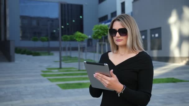 Schöne junge Frau mit Sonnenbrille am Tablet-PC in der Stadt. — Stockvideo