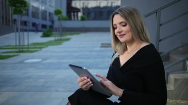 Şehirde tablet kullanan güzel bir genç kadın. İş kadınının elinde aygıtlar var.