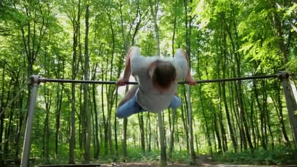 L'uomo entra per lo sport facendo esercizi di pull-up sulla barra orizzontale all'esterno. Maschio — Video Stock