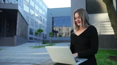 Dışarıdaki teknolojiyi kullanarak. Çalışan genç bir kadın. Dizüstü bilgisayarı olan iş kadını