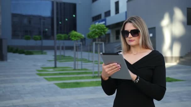 Piękna młoda kobieta w okularach przeciwsłonecznych za pomocą tabletu w mieście. — Wideo stockowe