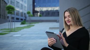 Şehirde tablet kullanan güzel bir genç kadın. İş kadınının elinde aygıtlar var.