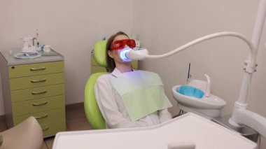 Mavi cihaz, Whitening sonuçları, diş hekimliği. Klinikte koruyucu gözlük takan hastaya mavi ışık aygıtı kullanılarak diş beyazlatma işlemi yapılıyor.