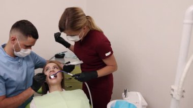 Ağız sağlığı, diş bakımı, dişçi aletleri. Diş hekimi asistanı dişçi koltuğunda gülümseyen bir hastanın dişlerini temizliyor..