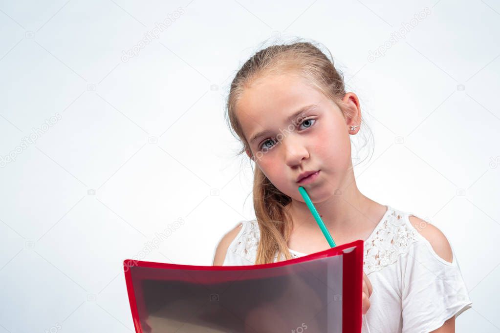 A cute 10-year-old caucasian schoolgirl looking a bit worried while holding a pencil against her chin