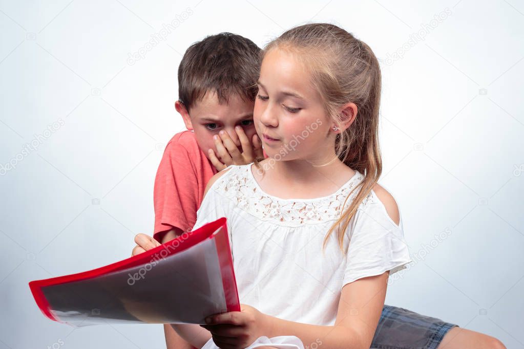 Caucasian schoolchildren studying, a nice girl holding notes, explains a boy who does not understand the subject and holds his hand against his mouth. Education concept